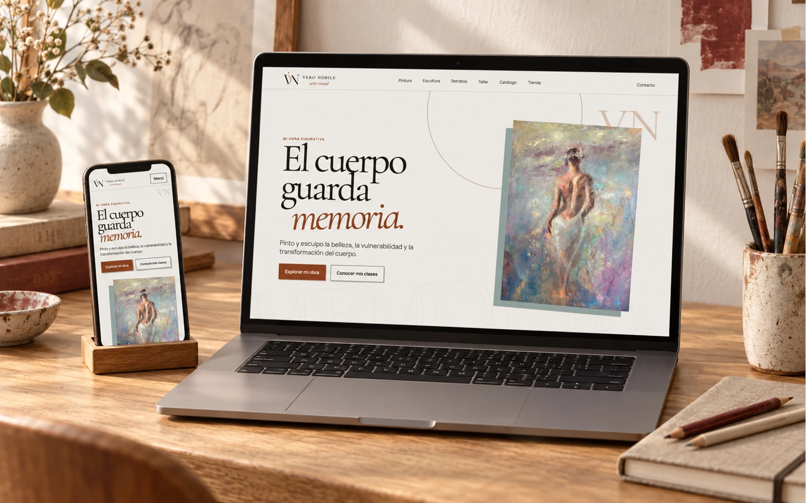 Composición de la web de Vero Nobile en computadora y celular sobre un escritorio de artista en una escena conceptual, proyecto en construcción